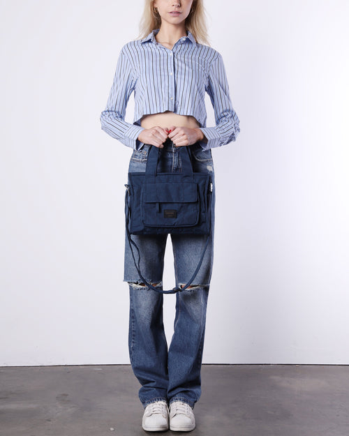 Woman wearing a blue striped crop shirt and ripped jeans holding a ZIMEGO Bags navy blue tote